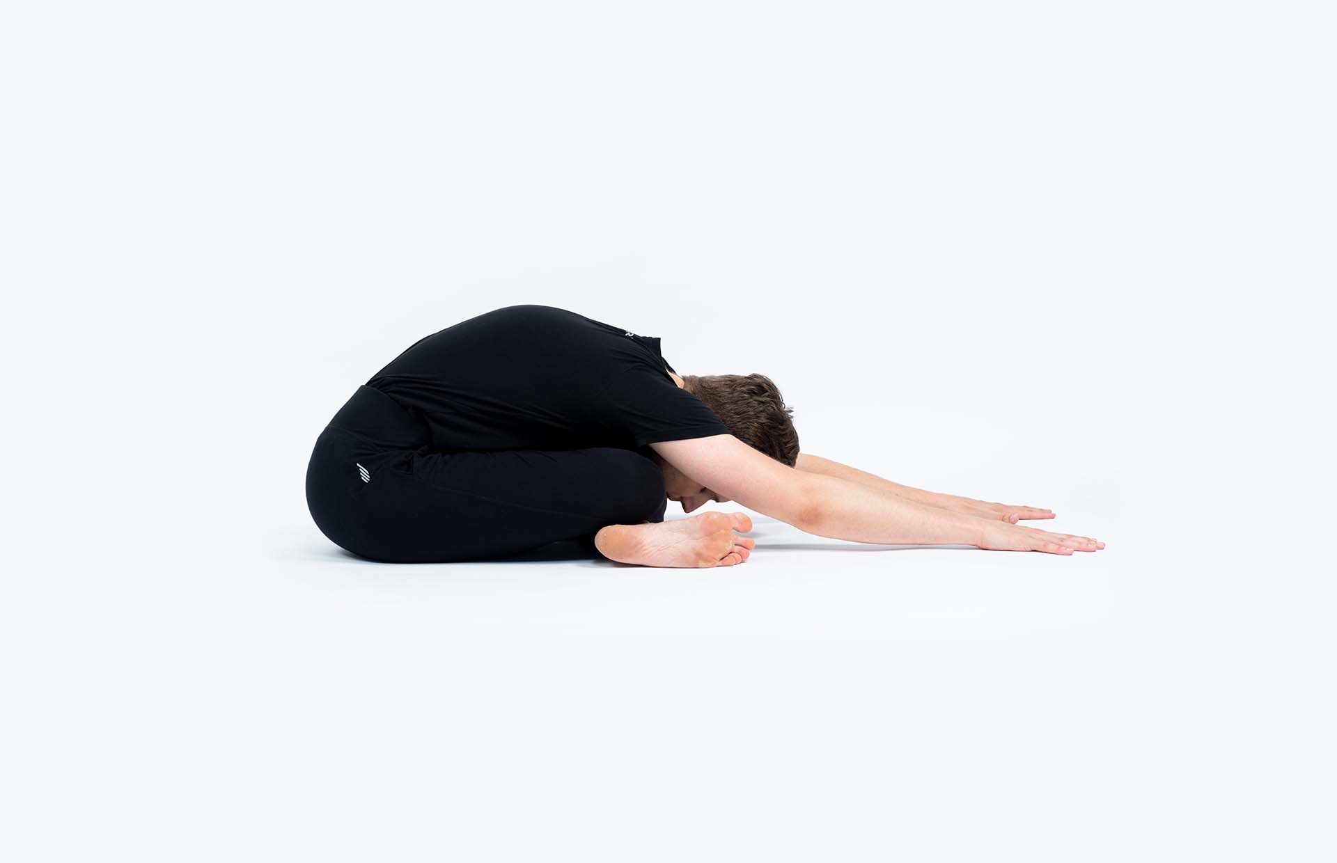 A person reaching forward in Agni Stambhasana (Knee to Ankle Pose)