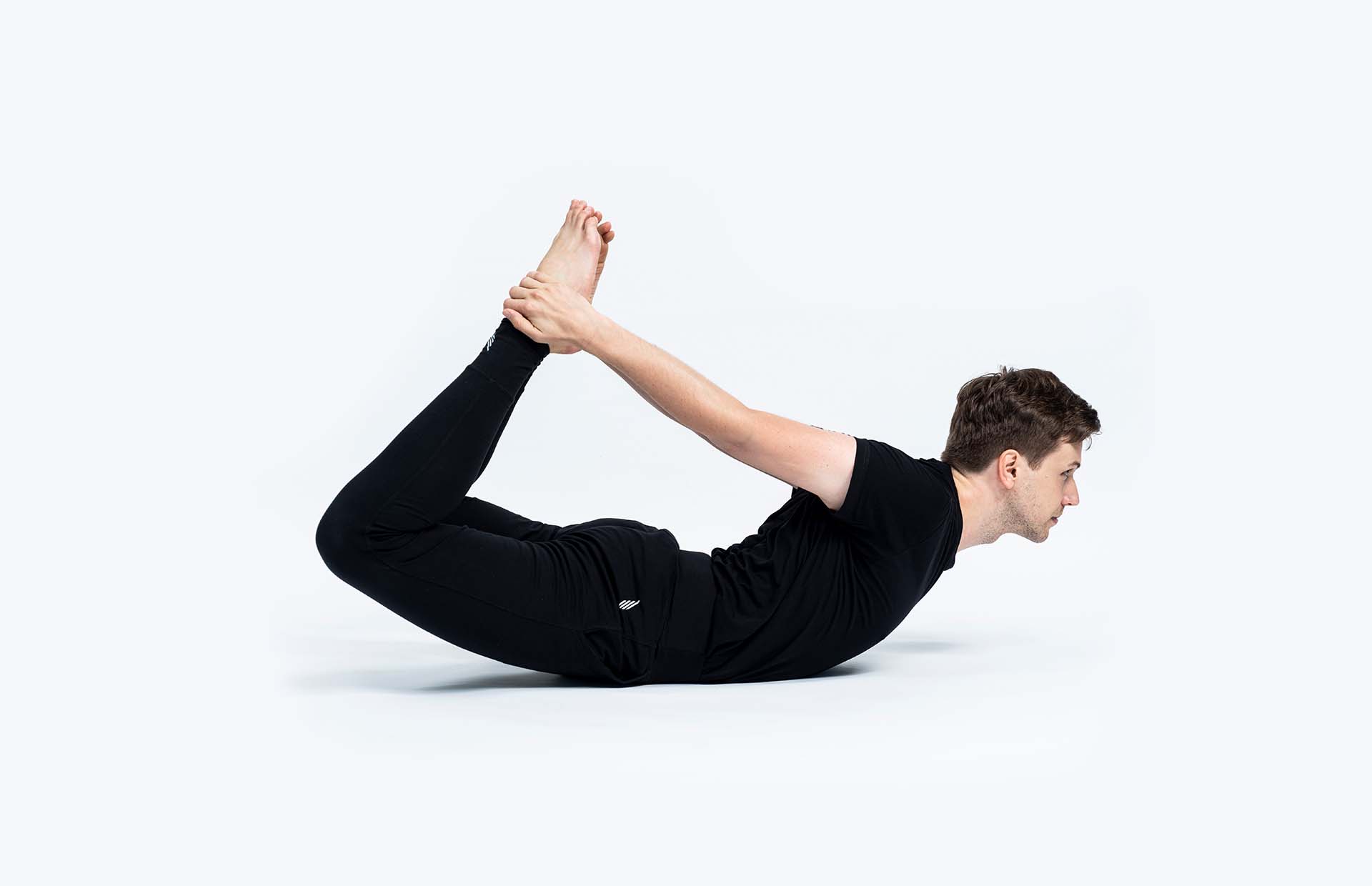 A person extending into Dhanurasana (Bow Pose)