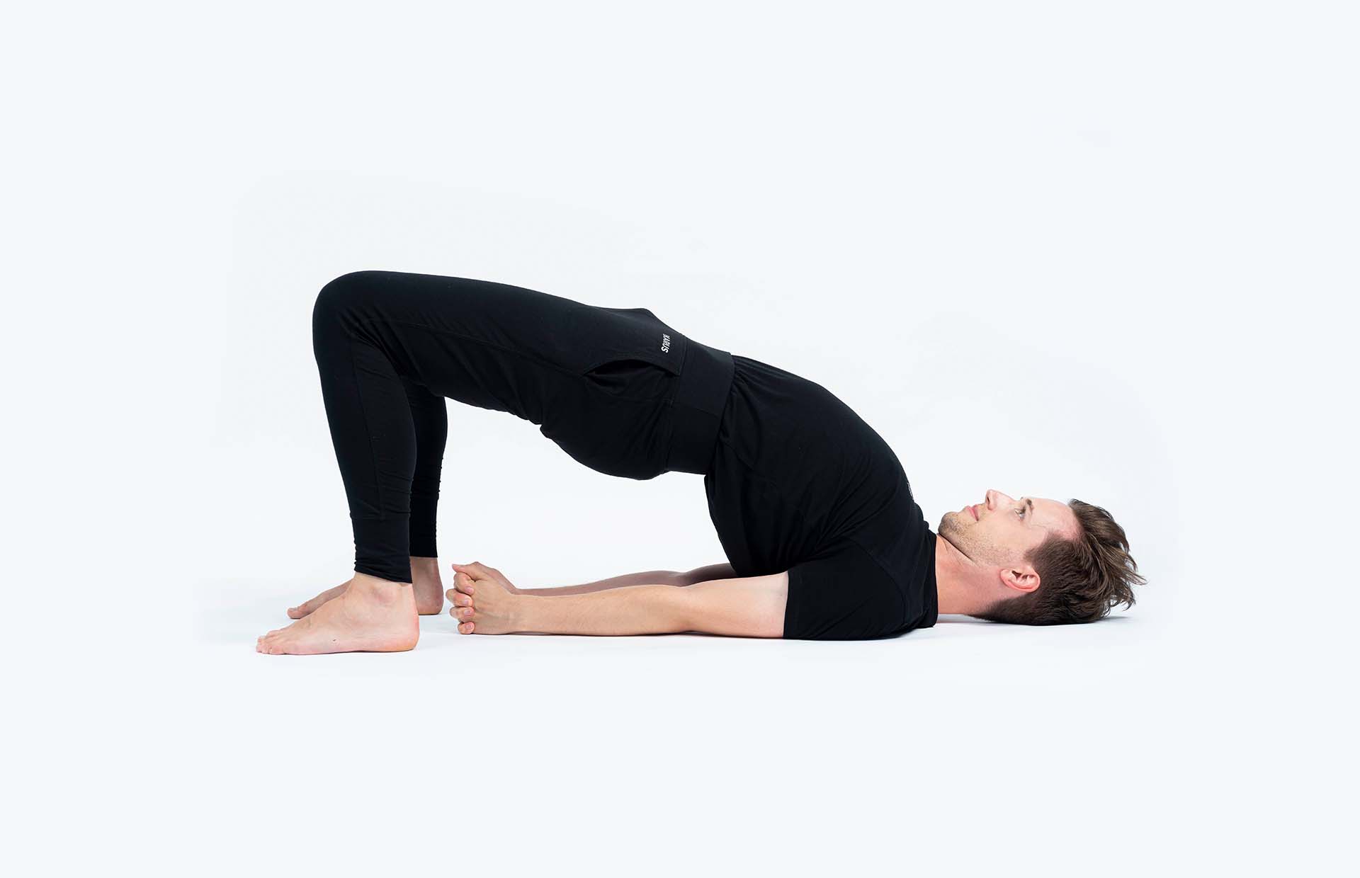 A person lifting into Setu Bandha Sarvangasana (Half Wheel Pose)