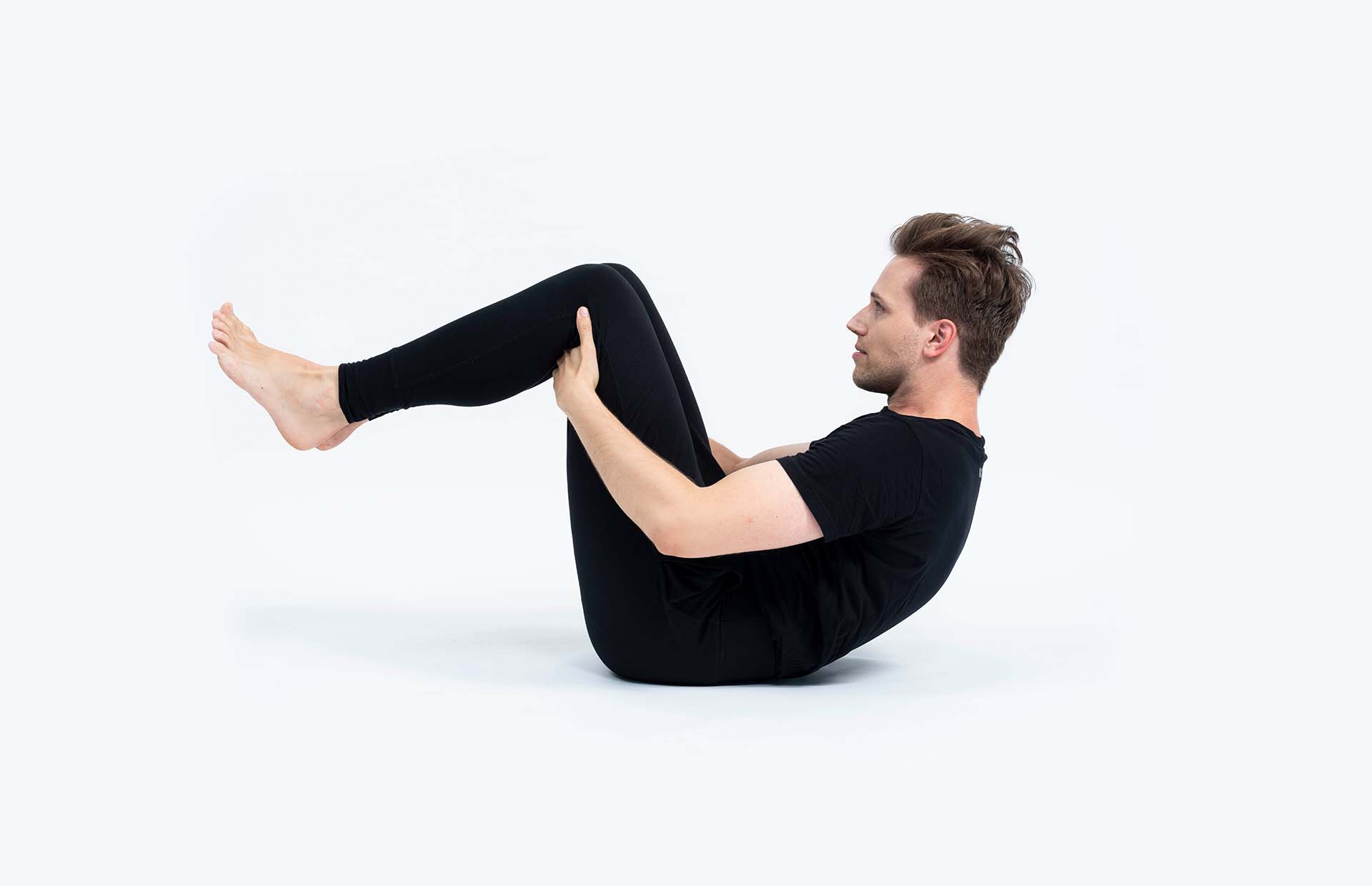 A person rolling forward with hands tucked behind their knees